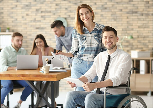 mężczyzna na wózku inwalidzkim pracuje w biurze razem z zespołem ludzi